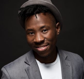 Portrait of attractive young black male studio with hat cheesy smile on dark background Portrait of attractive young black male studio with hat cheesy smile on dark background. Studio shot